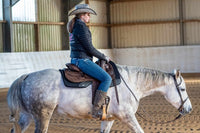 Eine Frau reitet ein weißes Westernpferd mit Westernpad und Westernsattel